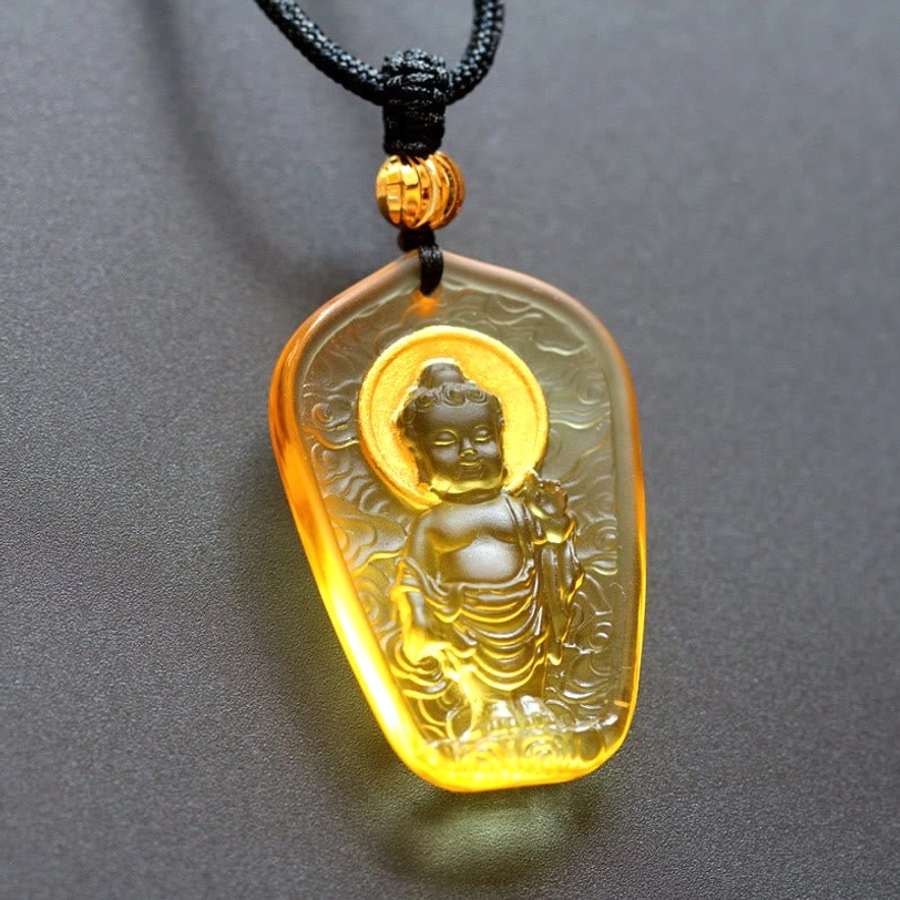 Glowing Amber Baby Buddha Liuli crystal pendant necklace, translucent golden crystal with gilded Buddha figure, illuminated halo, artistic light glow effect