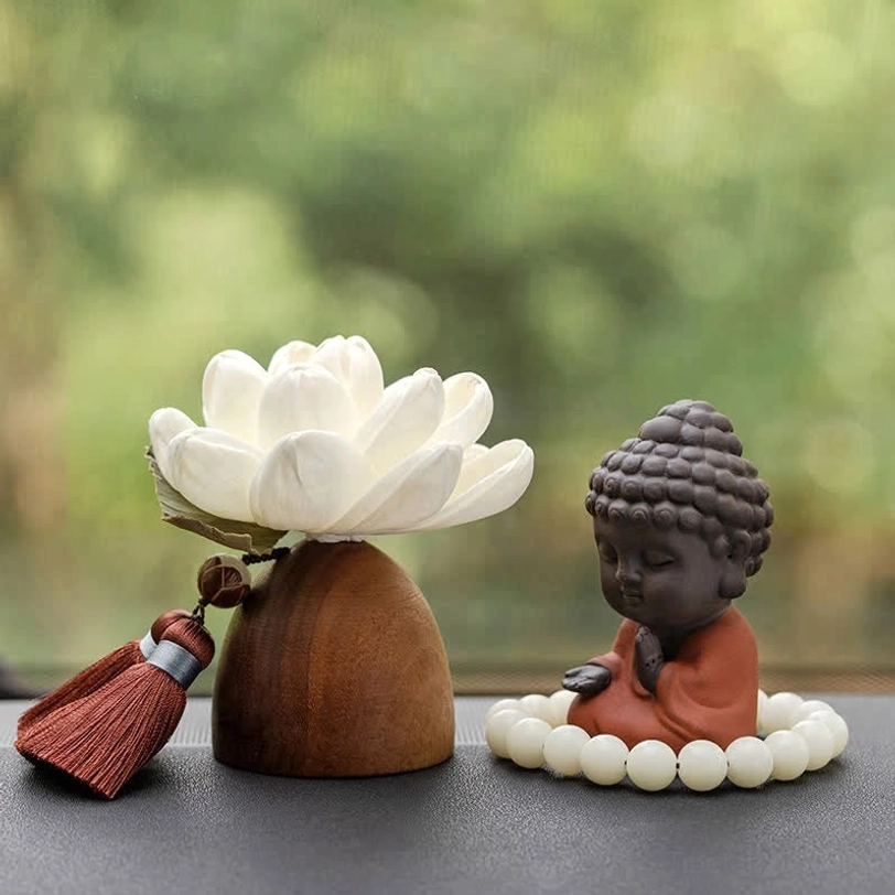 Mini Buddha figurine with lotus holder and prayer beads on dark peach wood base, flat lay composition