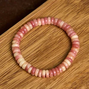 Handmade camel bone protection bracelet featuring creamy beige to warm pink gradient beads, flat disc design on wooden surface