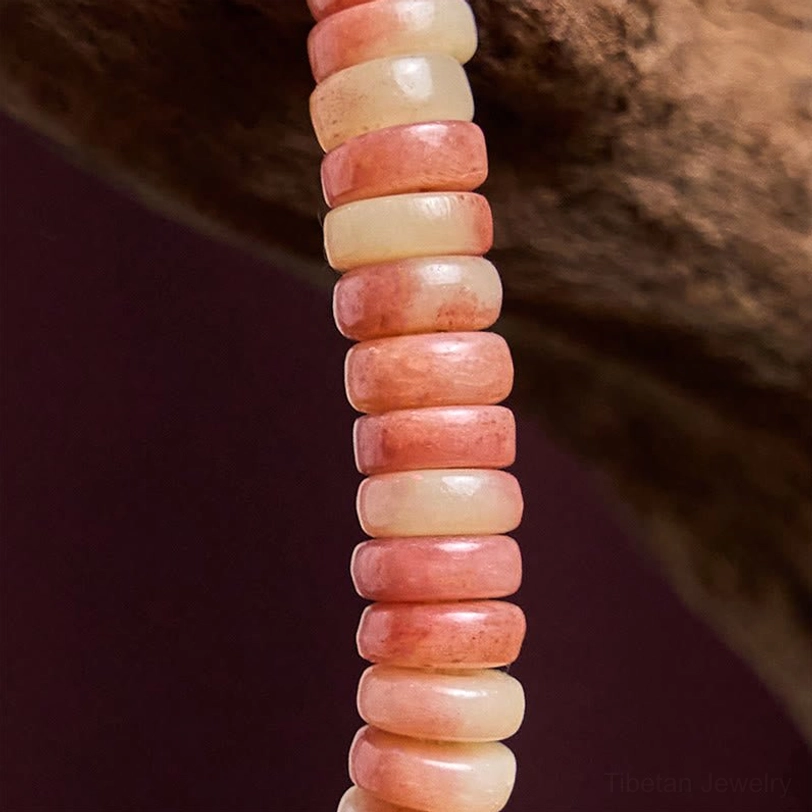 Close-up macro shot of polished camel bone disc beads showing natural texture, gradient pink to cream tones stacked arrangement