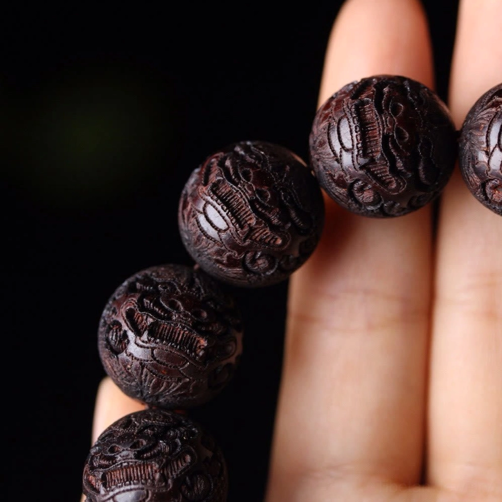 Macro detail of carved rosewood beads showing intricate embossed patterns and texture