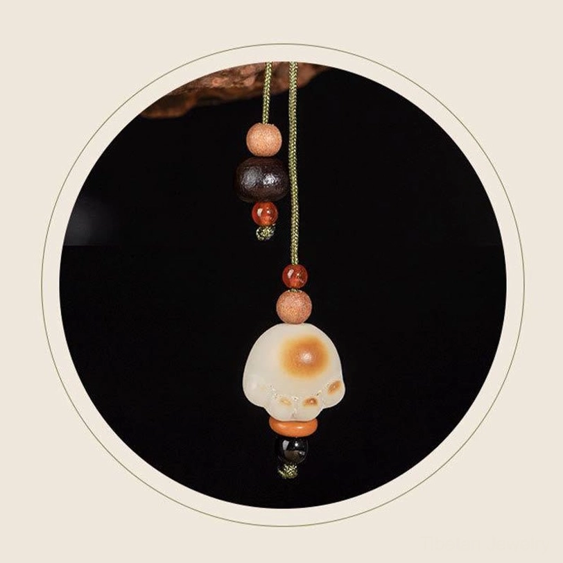 Cat paw bodhi charm pendant with two-tone design and mixed accent beads on green hanging cord, close-up front view with circular dark background frame