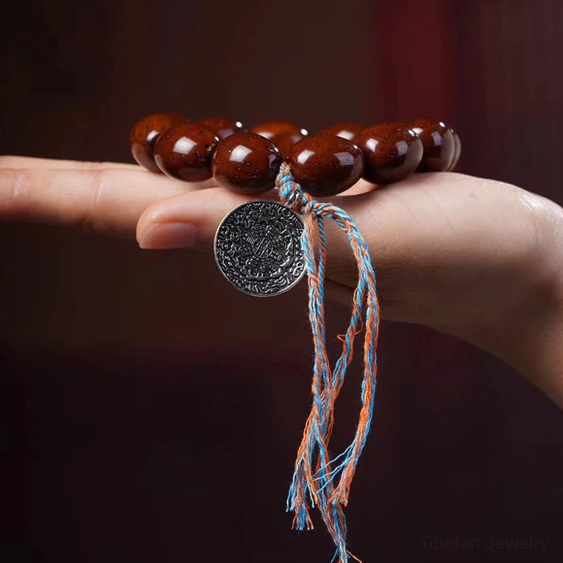 Chinese zodiac bracelet with oval reddish brown bodhi beads and silver pendant on light fabric background
