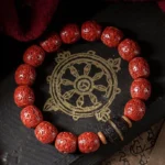Cinnabar and ebony wooden blessing bracelet displayed on Buddhist scripture mat, showing carved red barrel beads with black ebony spacer beads from overhead view