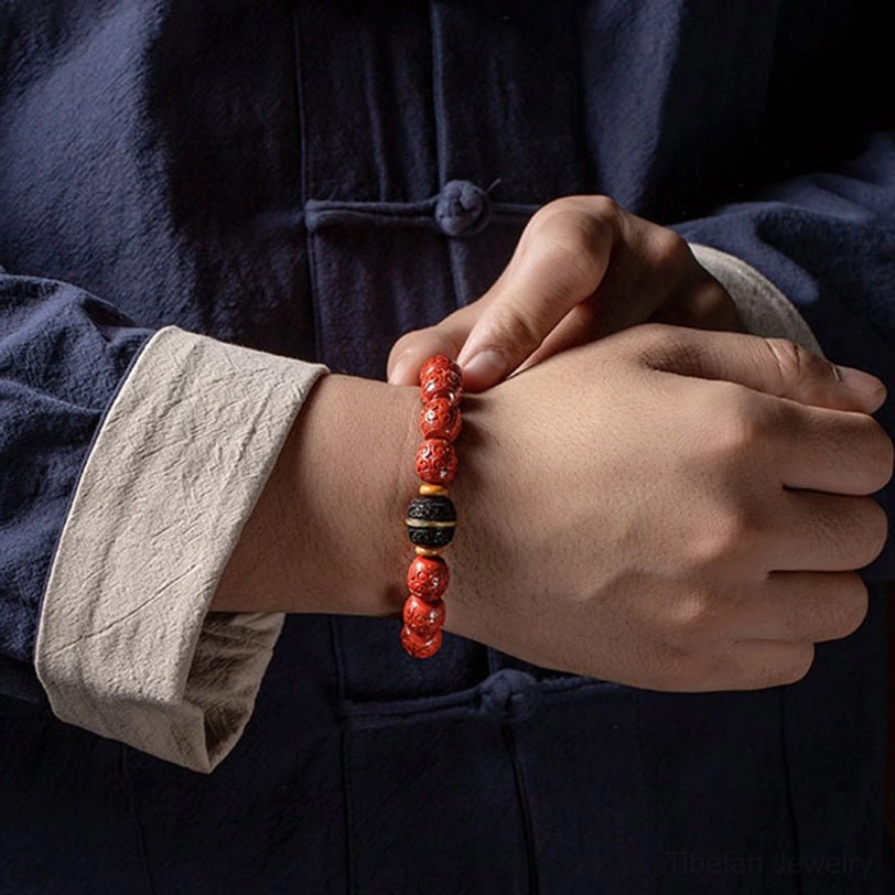 Person wearing cinnabar ebony prayer beads bracelet on left wrist, front double-hand view in traditional Chinese style clothing