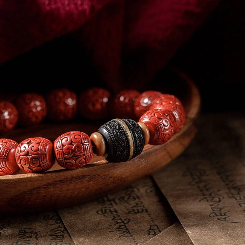 Close-up detailed view of cinnabar ebony bracelet showing intricately carved red barrel beads and black ebony spacer details on wooden tray