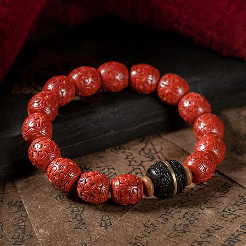 Cinnabar and ebony wood blessing bracelet arranged in circular pattern on Buddhist scripture paper background, overhead view