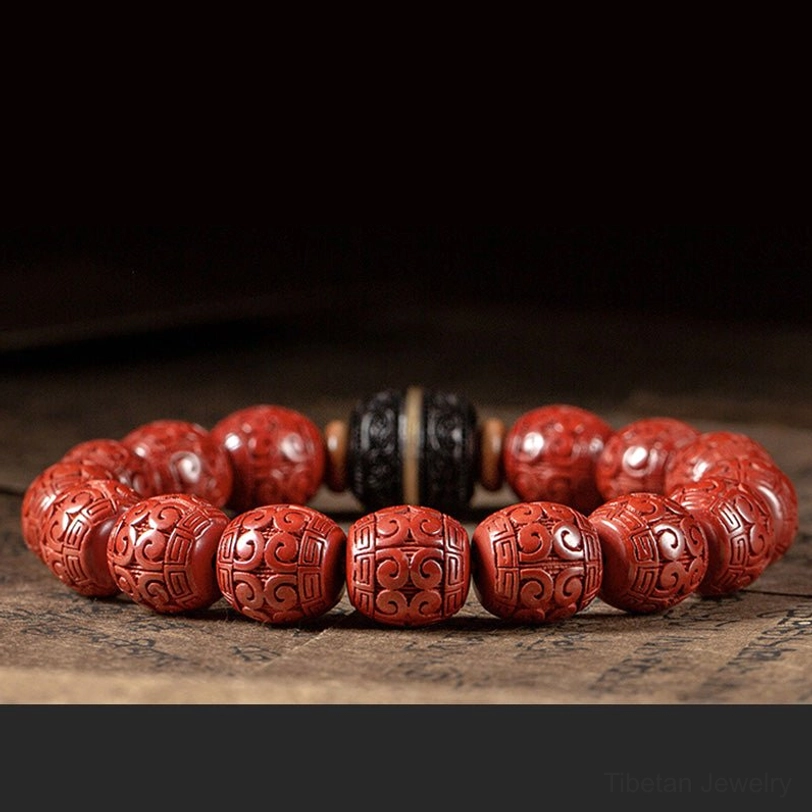 Two matching cinnabar and ebony blessing bracelets side by side on dark wooden surface with Buddhist scripture paper, flat lay view