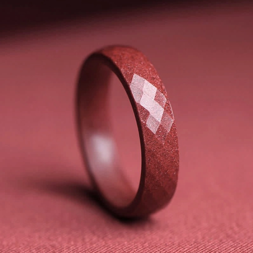Faceted cinnabar ring close-up displaying rhombus cut surface pattern and sparkly crimson granular finish