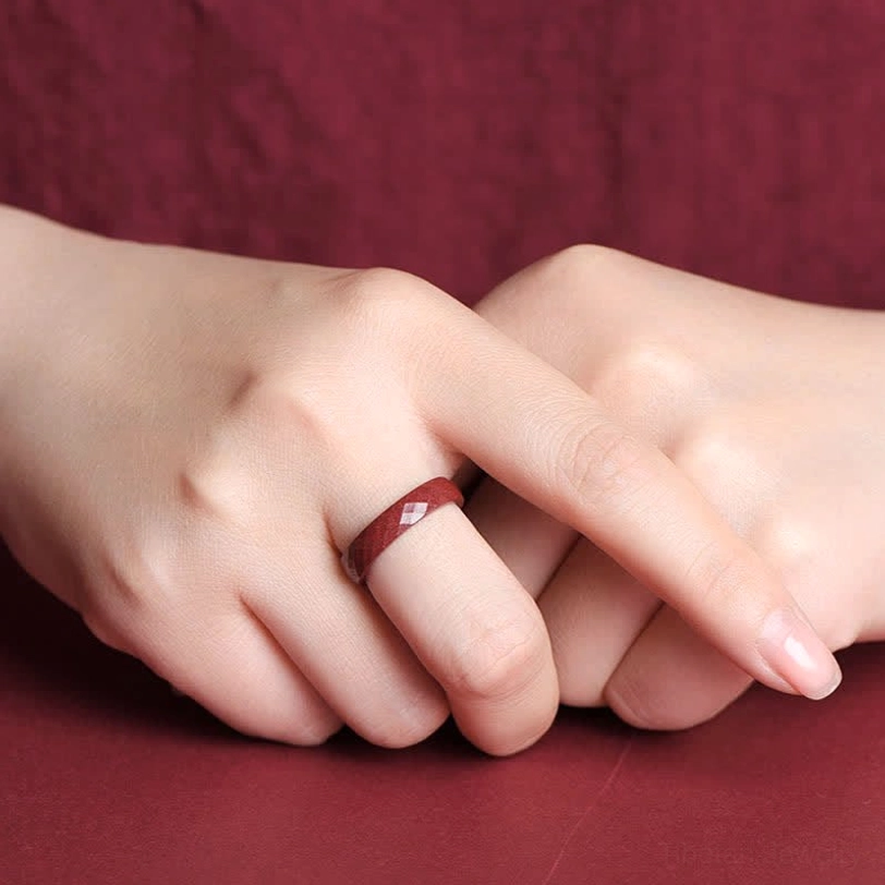 Faceted cinnabar om mani blessing ring on finger showing comfortable wear and faceted surface design detail