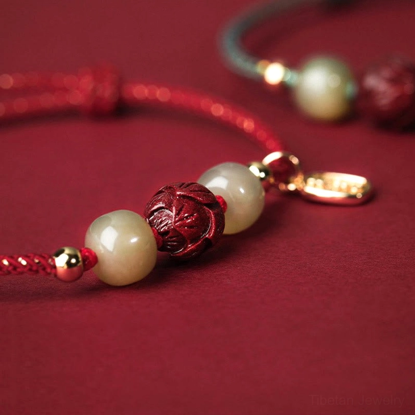 Close-up side view of cinnabar lotus bead and gold-plated metal hardware on jade bracelet