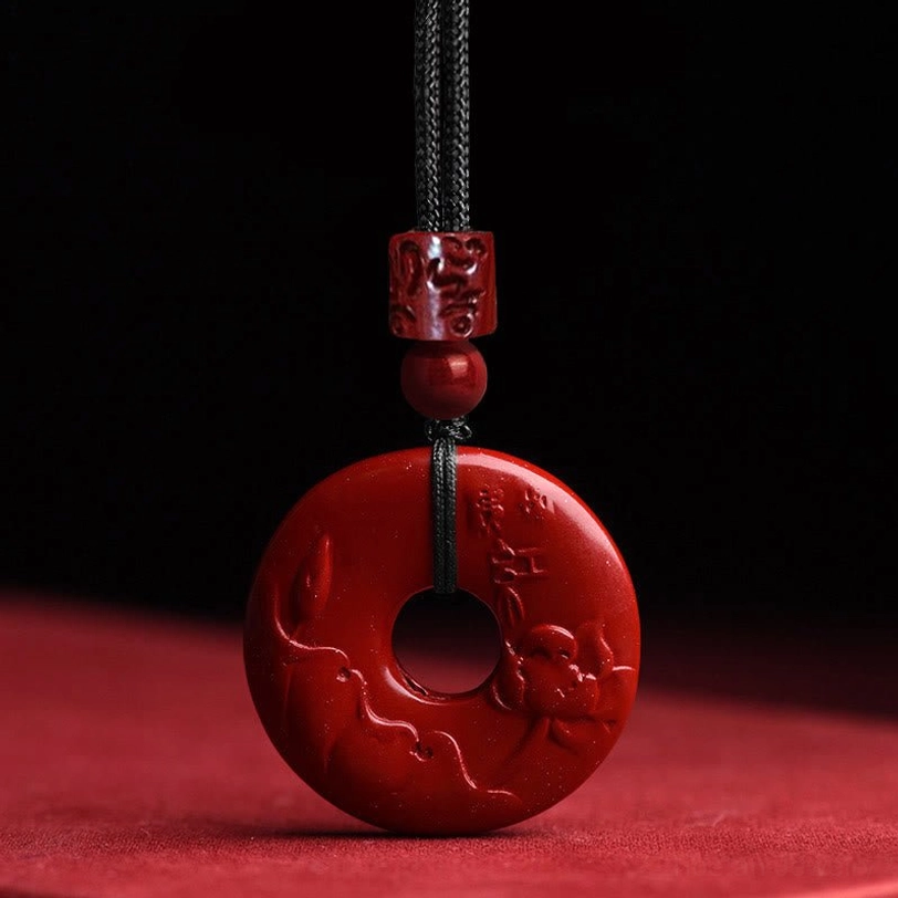 Cinnabar lotus-carved peace buckle pendant necklace with lotus and cloud engravings on red stone background, front view