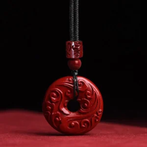 Cinnabar lotus peace buckle pendant necklace with hand-carved cloud patterns on red fabric background, front close-up view