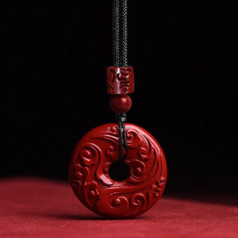 Cinnabar lotus peace buckle pendant necklace with hand-carved cloud patterns on red fabric background, front close-up view