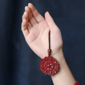 Hand-carved cinnabar lotus pendant held on human palm, showing intricate detail and deep crimson color of the blessing necklace