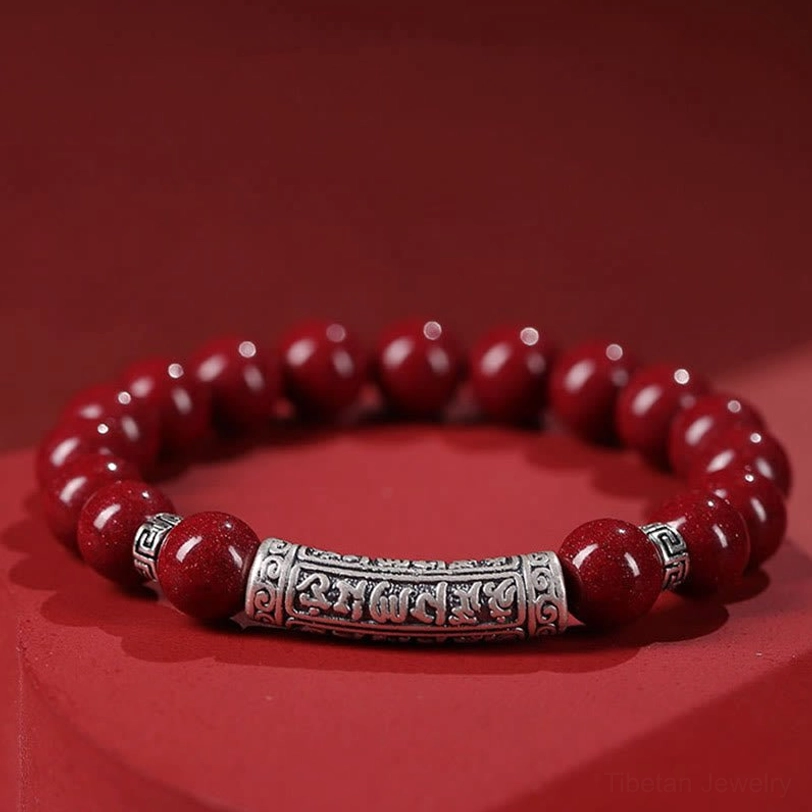 Cinnabar Om Mani Padme Hum bracelet three-quarter angle displaying glossy red cinnabar beads and vintage sterling silver engraved charm