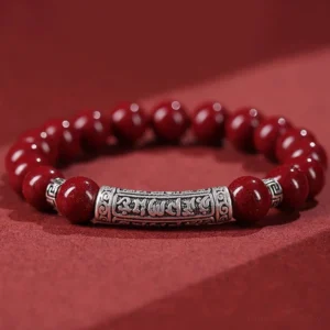 Cinnabar Six True Words blessing bracelet top-down view showing deep red matte cinnabar beads with engraved sterling silver Om Mani Padme Hum charm tube