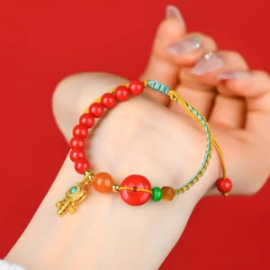 Cinnabar peace buckle bracelet worn on wrist close-up side view showing the pendant and braided string design on red background