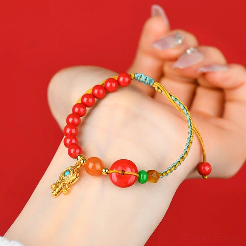 Cinnabar peace buckle bracelet worn on wrist close-up side view showing the pendant and braided string design on red background