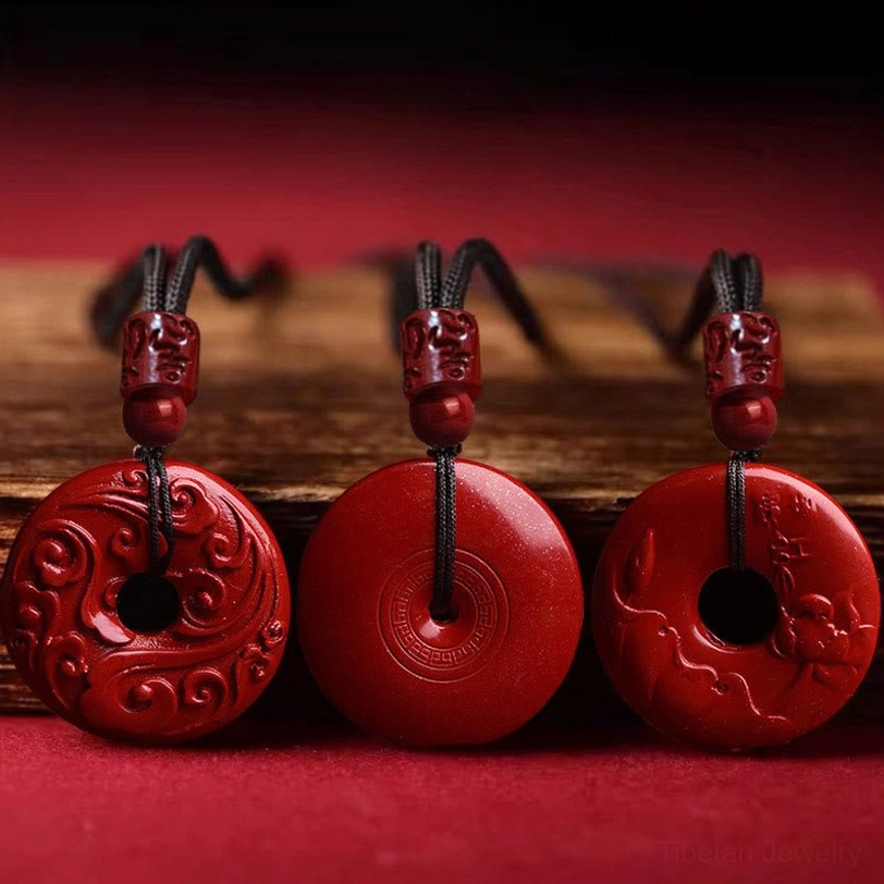 Three cinnabar peace buckle pendant variations showing carved and smooth surfaces on wooden display, flat lay product photography