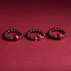 Three styles of cinnabar protection rings featuring PiXiu charm and round beads with precious metal accents on deep red background