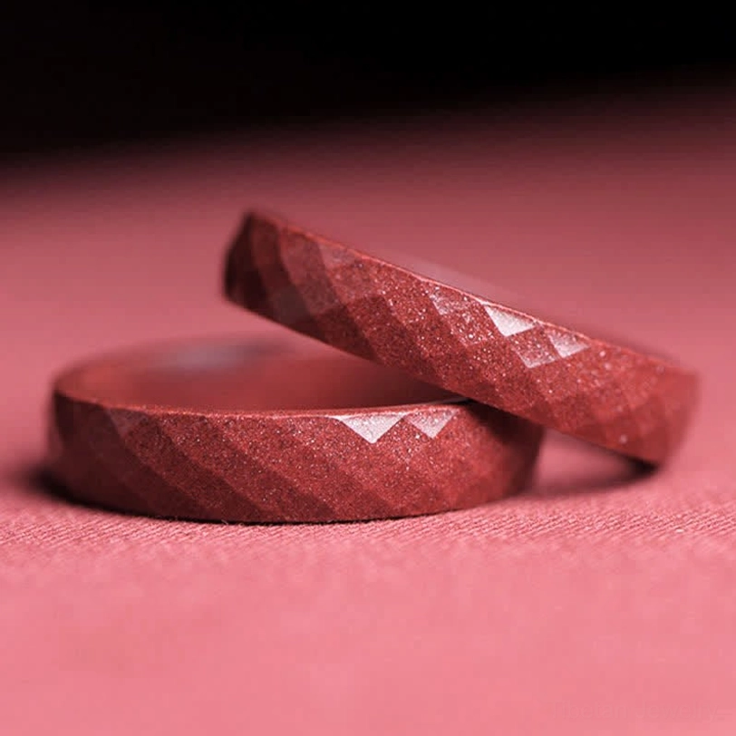 Two cinnabar blessing rings stacked display showing rhombus faceted surfaces and deep red sparkly natural stone texture