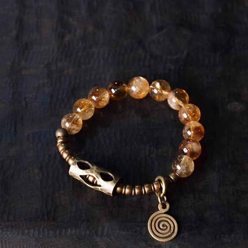 Flat lay overhead view of citrine protection bracelet with light yellow beads and vintage metal pendant