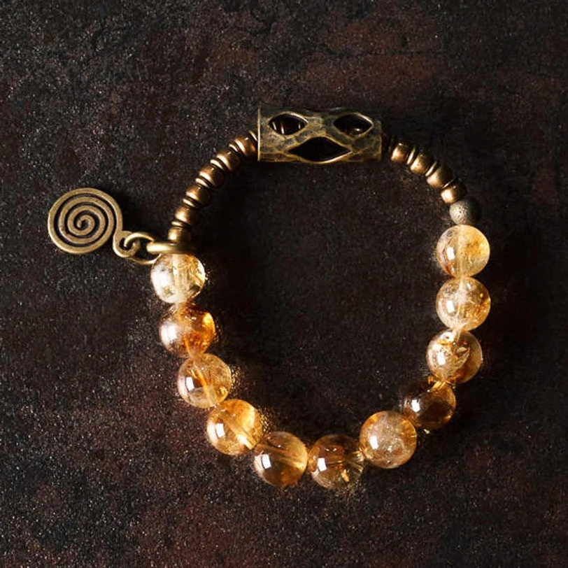 Side view of citrine 10mm bead bracelet showing spiral charm placement and hollow metal fastener detail