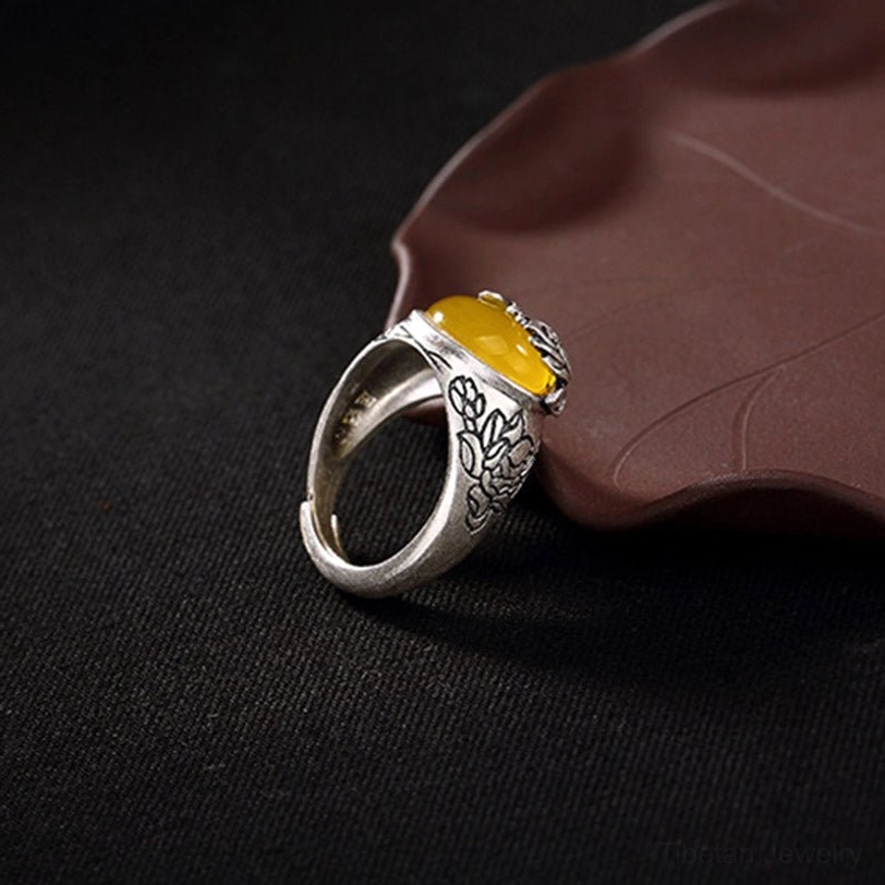 Front right angle of lotus citrine silver ring showing detailed embossed flower patterns on band with oval yellow gemstone and lotus accent