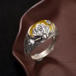 Citrine lotus adjustable ring featuring oval yellow gemstone with embossed silver lotus flower on ceramic lotus-leaf tray, front top-left view