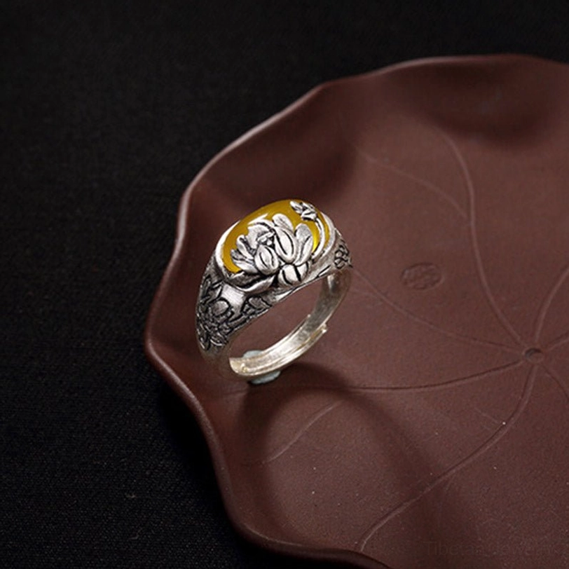 Left side profile of citrine lotus blessing ring showing embossed floral carvings on copper shank and oval yellow gemstone