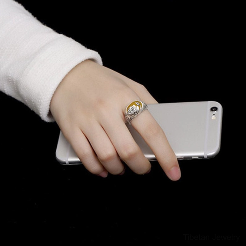 Citrine lotus adjustable ring worn on index finger with white sweater sleeve, showing ring in everyday hand wear