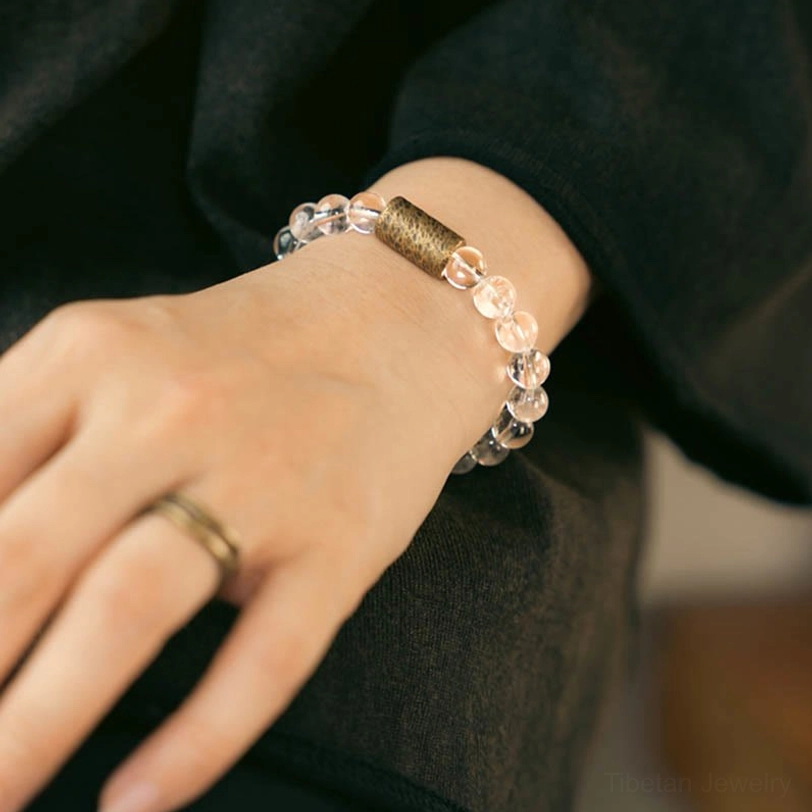 Person wearing clear quartz protection bracelet on left wrist paired with delicate finger ring, everyday wear style