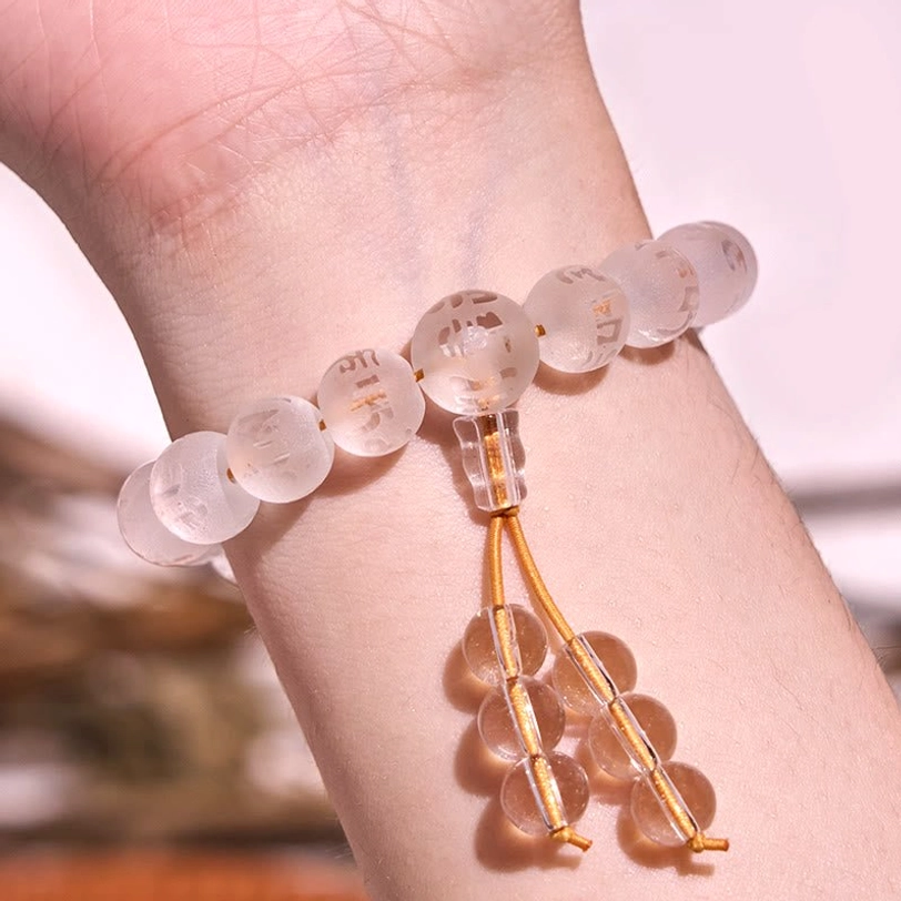 Clear quartz smooth bead bracelet worn on wrist with warm lighting