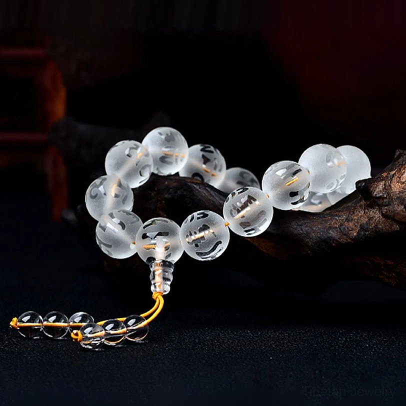 Clear quartz tibetan mantra bracelet with transparent round beads and yellow tassel pendant displayed on dark background