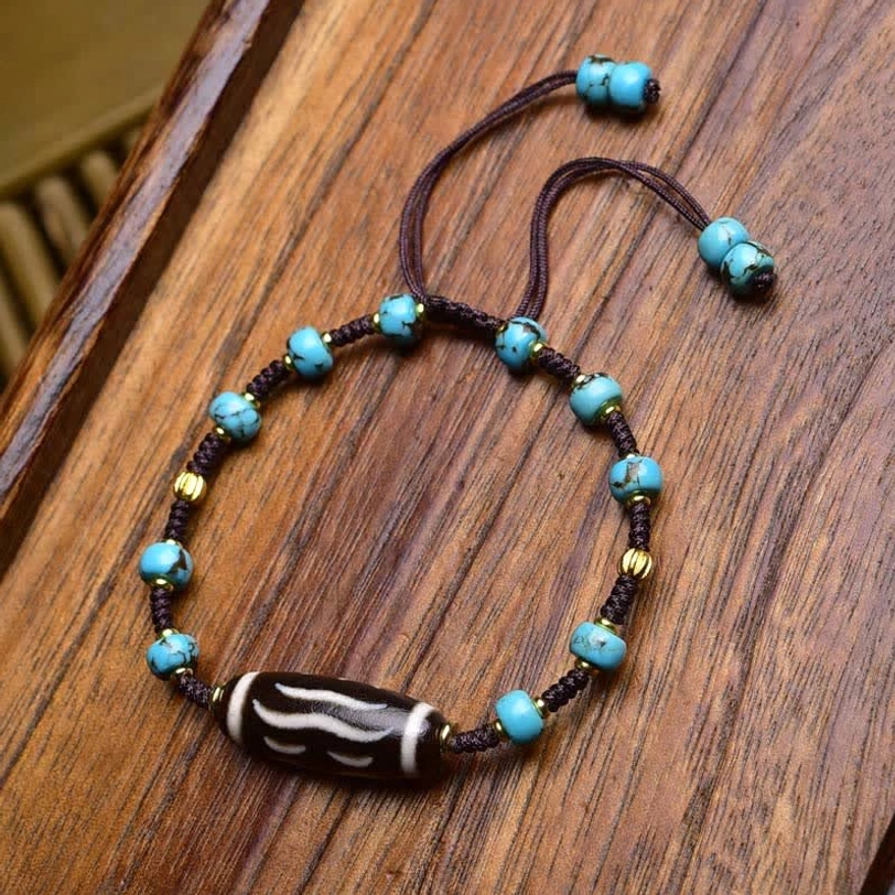Coconut bead Dzi protection bracelet with natural coconut spacers, dark beads, and silver metal accents on braided cord