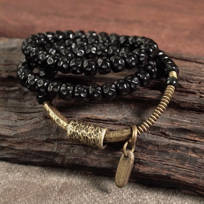Angled view of coconut shell brass bracelet - triple wrap design with hammered brass detail and hanging tag pendant