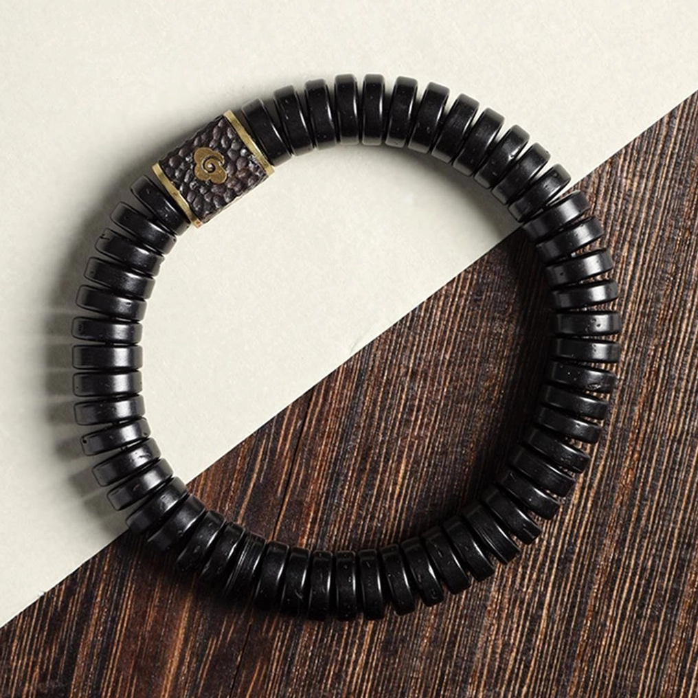 Coconut shell beaded bracelet with embossed cloud metal accent displayed on wooden texture background