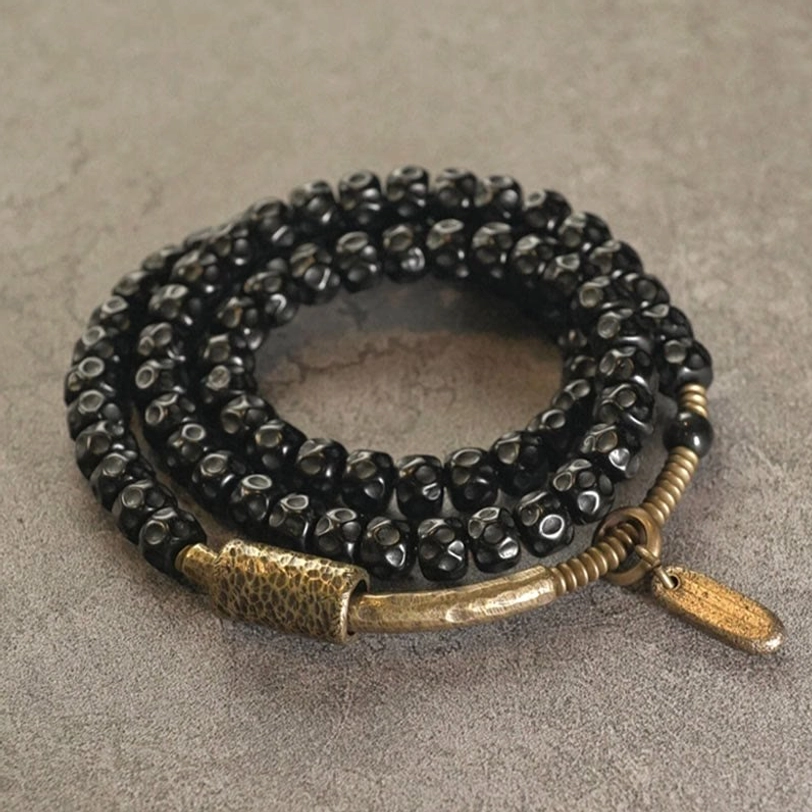 Close-up flat lay of handmade coconut shell bracelet - triple wrap with faceted beads and elongated metal tag charm