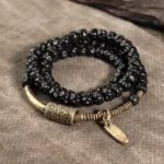 Coconut shell brass triple wrap bracelet flat lay - handmade beaded bracelet with antiqued brass hardware and metal tag charm