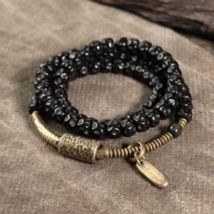 Coconut shell brass triple wrap bracelet flat lay - handmade beaded bracelet with antiqued brass hardware and metal tag charm