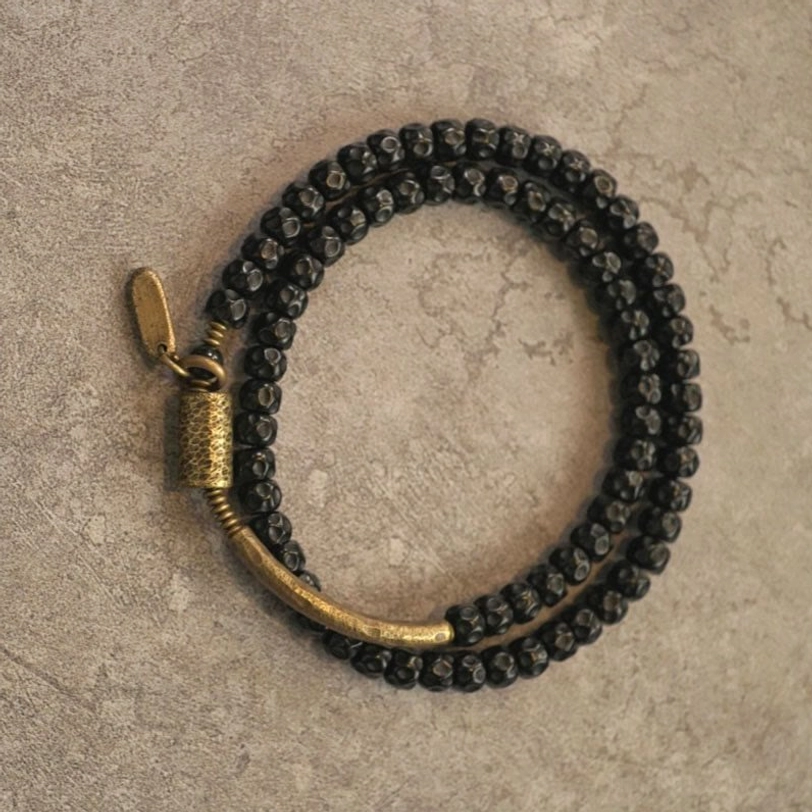 Double wrap coconut shell beaded bracelet - black faceted beads with antiqued brass clasp on neutral background