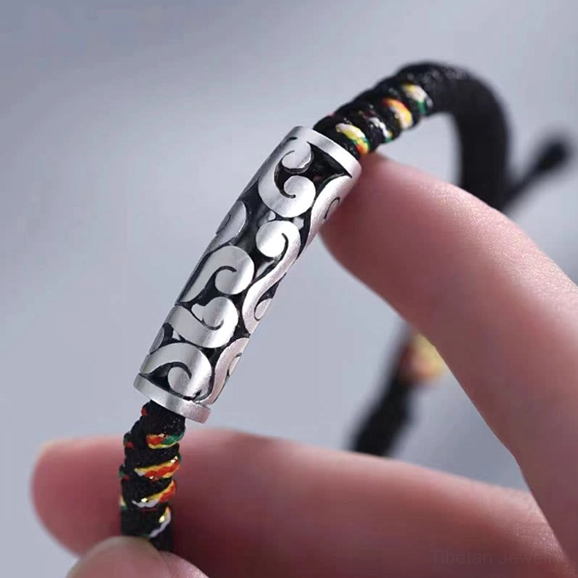 Close-up detail of silver cloud charm on tibetan luck bracelet showing intricate embossing and braided rope texture