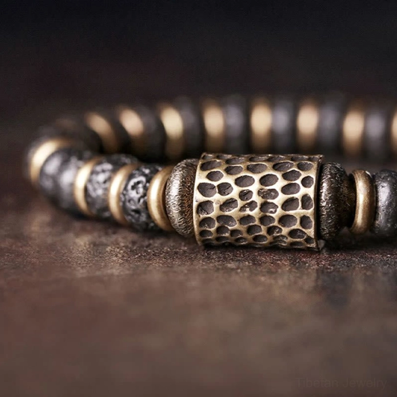 Extreme close-up of hammered copper barrel bead paired with lava rock beads showing artisanal craftsmanship