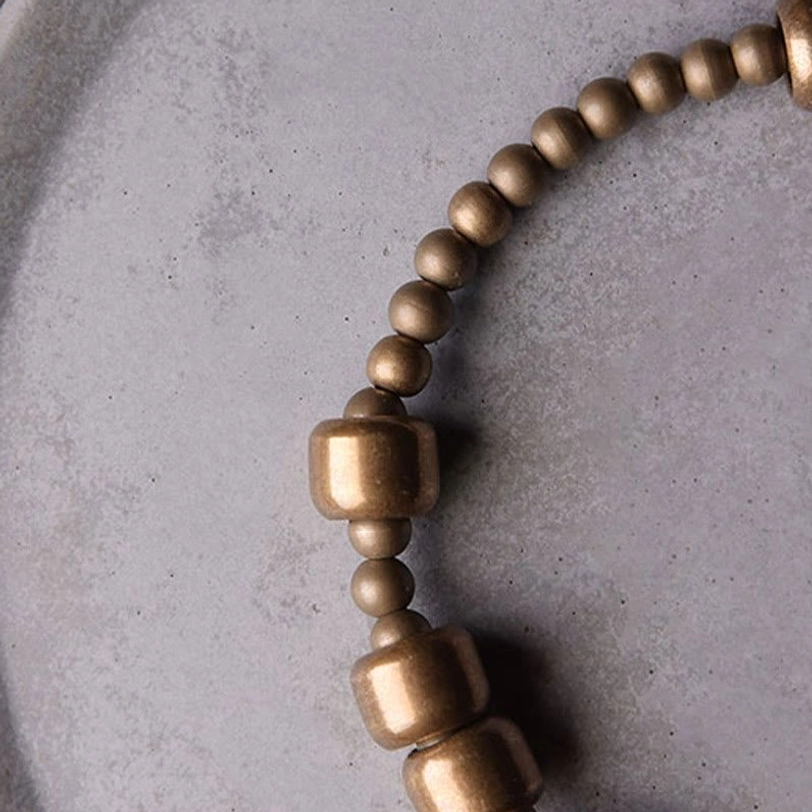 Angled close-up of stacked copper barrel beads paired with small round spacer beads on ceramic plate