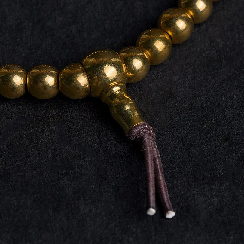 Macro close-up of polished copper guru bead connector with brown leather tassel detail