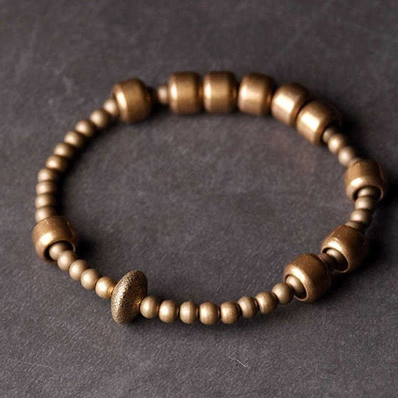Top-down view of copper beaded bracelet with matte finish showing mixed bead sizes and central rondelle accent