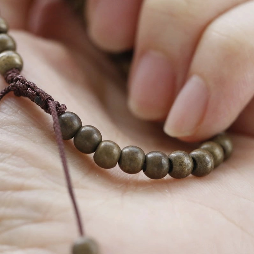 Close-up macro view of adjustable braided cord closure with bronze spacer beads held in hand