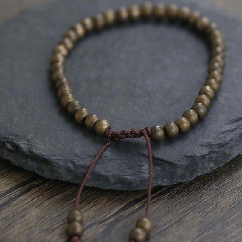 Close-up front view of copper beads bracelet highlighting braided center knot and tassel bead accents