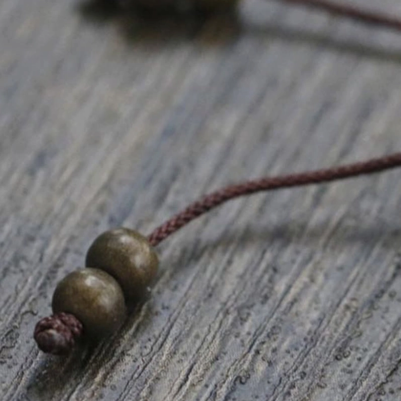 Overhead angle of copper brass beads bracelet showing complete bead arrangement and decorative tassel design